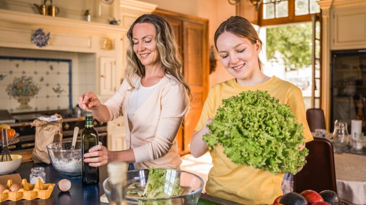 Teenage girl and mother preparing a balanced meal with fruit, vegetables, and nutritious foods to support healthy growth during puberty.